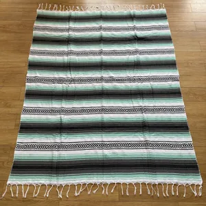Woven Mexican blanket with diamond jacquard pattern and fringes, ideal for beach and picnic.