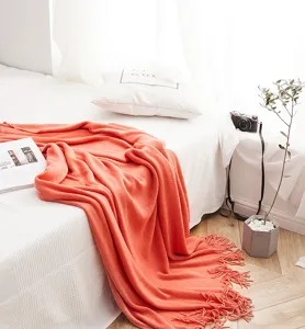 Detailed shot of the cozy orange knitted throw blanket with fringes, perfect for bedroom decor.