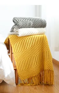 Knitted throw blanket detail with tassel design, cozy Nordic style sofa blanket for bedroom decor.
