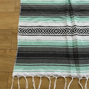 Close-up detail of a woven Mexican blanket featuring mint green, black and white stripes.