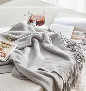 Grey knitted throw blanket with elegant fringe detail for cozy living room decor