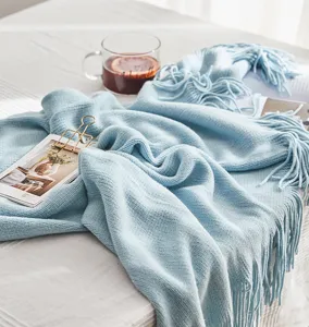 Soft knit throw blanket in light blue with elegant fringe detail for cozy living room decor.