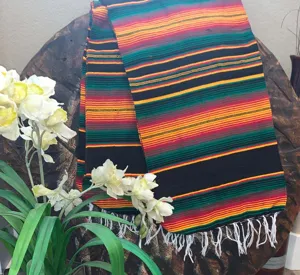 Detailed shot of a colorful woven Mexican serape blanket with fringe, lifestyle display.