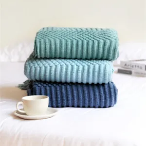 Detailed view of folded knitted Nordic sofa throw blanket with tassel design in multiple colors.