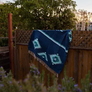 Woven jacquard beach blanket with Mexican Aztec tribal geometric pattern and fringe decor.