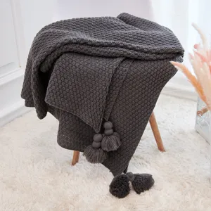 Dark grey knitted throw blanket with pom pom tassels, cozy sofa cover and home decor blanket.
