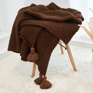Brown knitted blanket closeup detail with cute tassels, cozy home decor style and soft texture.