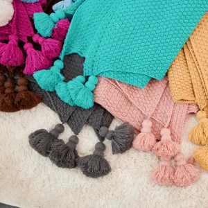 Close-up of Nordic knitted throw blanket with textured pineapple pattern and lovely tassels.