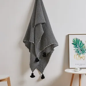 Detailed shot of a black and white knitted throw blanket with tassels for home decor.