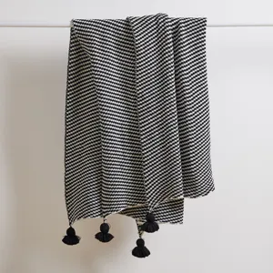 Knit tassel blanket detail close-up showcasing stylish black and white wave pattern.
