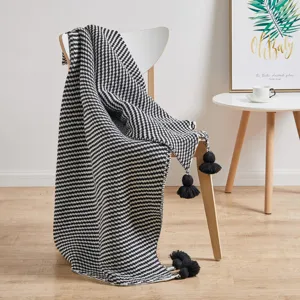 Black and white knitted blanket with tassel balls, nordic style cozy home decor throw.