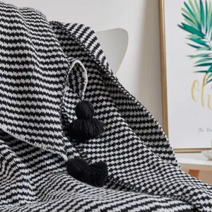 Nordic black and white striped knitted throw blanket with tassels and pom poms for home decor.
