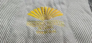 Close-up detail of grey chevron knit throw blanket featuring elegant embroidered logo accent.