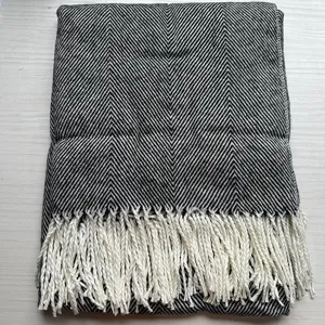 Close-up view of stylish black and white herringbone throw blanket with elegant fringe.