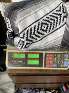 Close-up detail of the woven Mexican blanket with geometric fringe pattern shown in factory setting.
