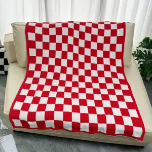 Red and white checkerboard blanket detail view, soft plush fabric texture for cozy sofa.