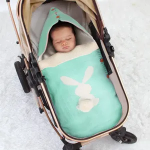 Detailansicht des gestrickten Babyschlafsacks mit süßem Hasen-Design im gemütlichen Kinderwagen.