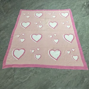 Pink knit blanket with white heart patterns and dark pink border for cozy home decor detail