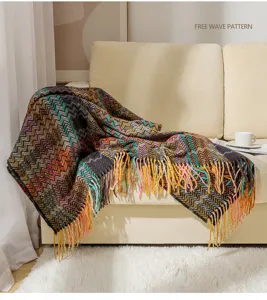 Cozy bohemian chevron woven blanket with tassels draped over a warm beige sofa in living room.