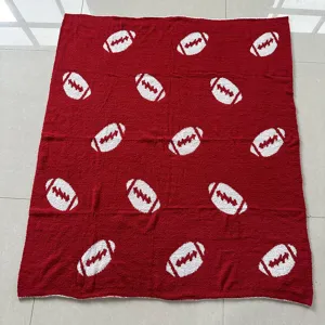 Coperta in maglia rossa con motivo di football bianco, primo piano del tessuto per la casa.