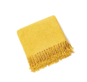 Yellow knitted throw blanket detail view featuring soft texture and elegant fringe edge.