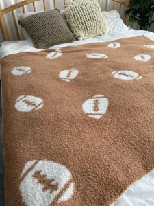 Coperta in maglia marrone con motivo a palla da football bianco per camera accogliente.