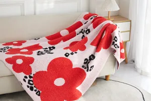 Cozy red floral throw blanket detail showing soft microfiber texture and warm living room sofa setup.