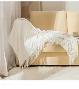 Cozy cream white fringe throw blanket detail shot, soft chenille sofa blanket texture view.