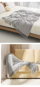 Detail close-up of grey knitted throw blanket with soft fringe, cozy home textile for sofa.