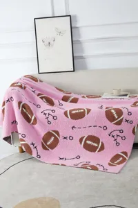 Accogliente coperta in peluche rosa con motivo da football, dettaglio in salotto.