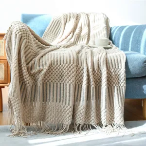 Cozy knitted throw blanket with tassels, elegant beige decorative sofa blanket for living room.