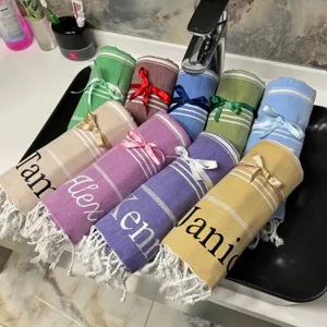 Personalized Turkish beach towels in assorted colors with custom embroidered names, perfect for beach.