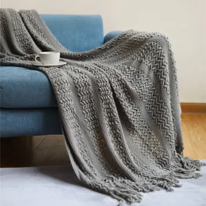 Plaid de lit ou canapé tricoté gris style nordique avec motif ajouré et franges douces et élégantes.