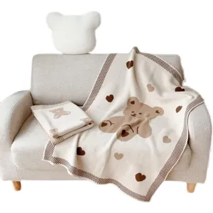 Couverture jacquard en tricot de coton doux avec motif d'ours et de cœur mignon sur le canapé.