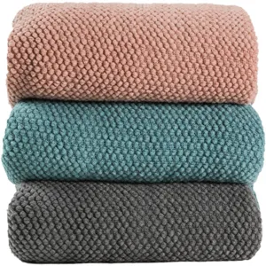 Knitted throw blanket set featuring three folded textured sofa blankets in various colors.