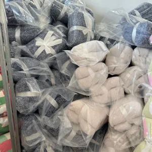 Detailed view of bulk packed knitted fleece blankets in clear bags with white ribbon ties.