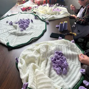 Handmade crochet blanket with purple flowers, cozy knitted throw for home decor and gifts.