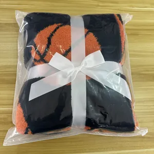 Detailed view of basketball plush throw blanket neatly folded with white ribbon in clear bag.