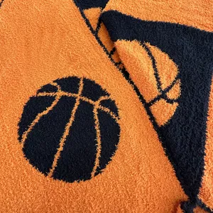 Close-up detail of the soft orange and navy knitted fleece blanket featuring a basketball pattern.