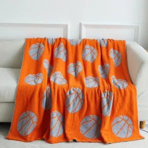 Detailed view of an orange knitted throw blanket featuring a stylish grey basketball pattern.