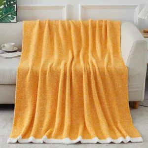 Detailed view of soft yellow chenille blanket with white border draped on cozy sofa home decor.