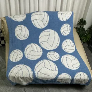 Detail shot of soft blue knitted throw blanket featuring white volleyball pattern for cozy sofa decor.