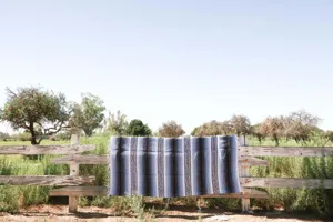 Vue detaillee en exterieur d'une couverture mexicaine tissee sur une cloture en bois.