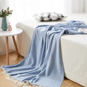 Detailed view of a soft blue herringbone woven throw blanket with fringe, cozy bedroom accent.
