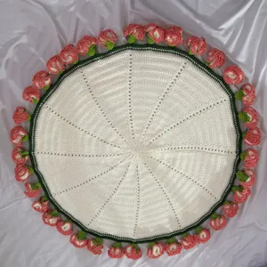 Handcrafted crochet round blanket with delicate pink rosebud border, cozy handmade home decor.