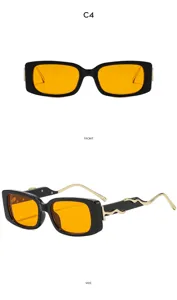 Detailansicht von Retro-Rechtecksonnenbrille mit goldenen Wellenbügeln und orangen Gläsern.