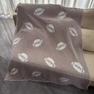 Accogliente coperta pelosa tortora con motivo da football bianco, perfetta per divano.