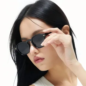 Primer plano de gafas de sol cuadradas negras con remaches de metal y lentes oscuras.