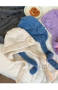 Detail view of handmade chunky knit balaclava hat featuring 3D floral accent and cozy woven straps.