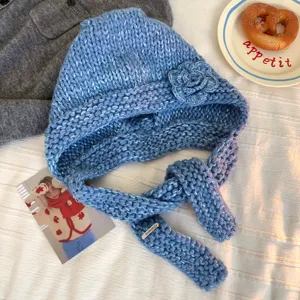 Detail shot of blue handmade chunky knit balaclava hat featuring a delicate 3D flower accent.
